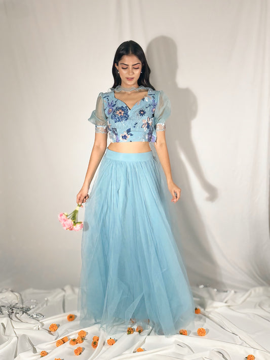 Woman wearing a light blue floral top and skirt with a white background