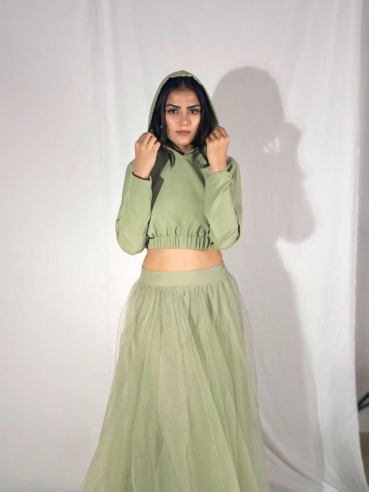 Person wearing a green hoodie and skirt set against a white background