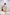Woman wearing a white pleated dress in a minimalistic setting. Freo