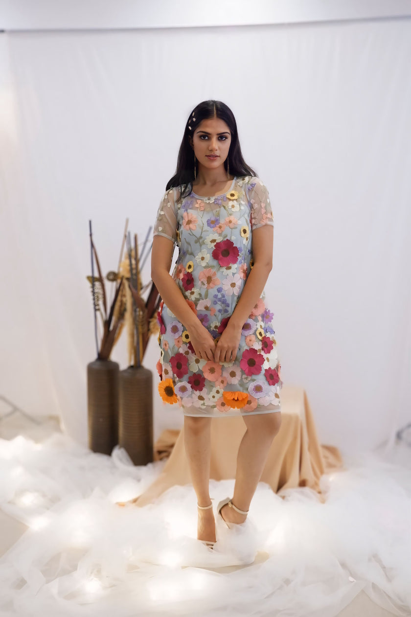 Woman wearing a floral dress standing in a minimalistic setting with white background and decorative elements.