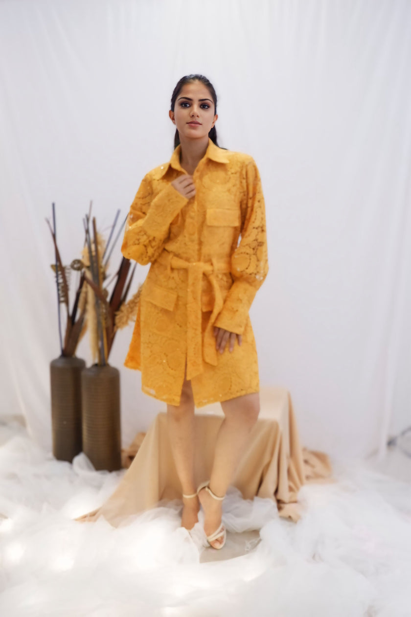 Woman wearing a yellow outfit standing in a minimalistic setting with white background and decorative elements. Freo