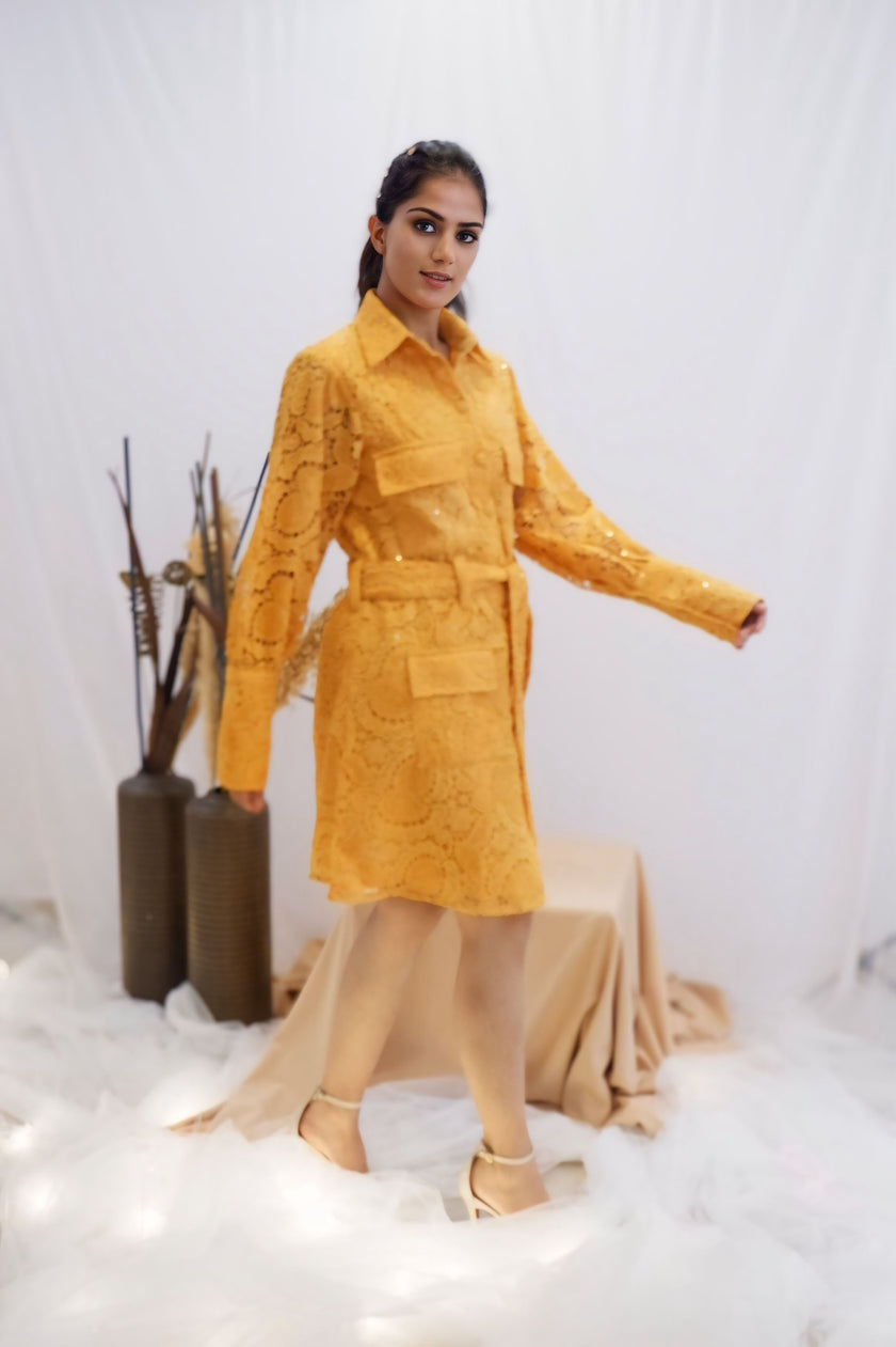 Woman wearing a yellow outfit standing in a minimalistic setting with white background and decorative elements. Freo