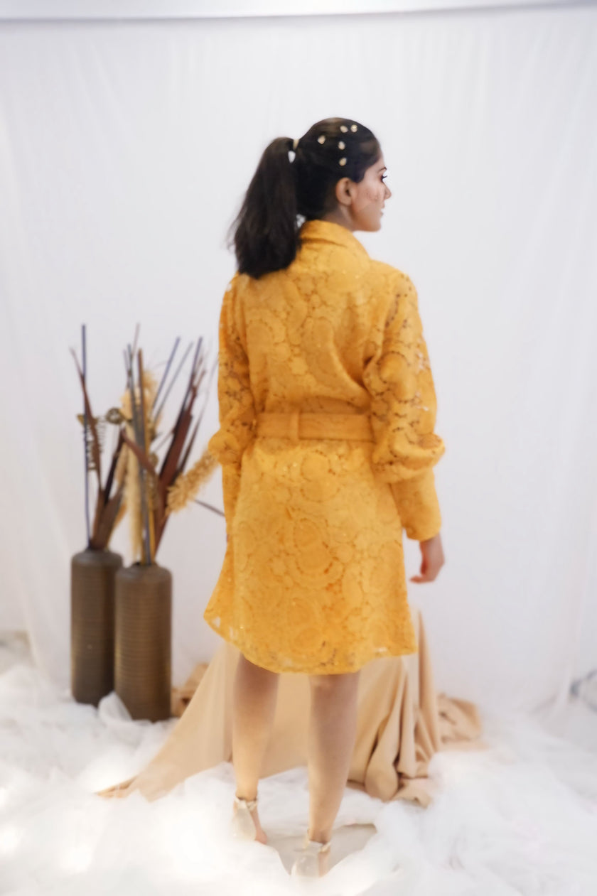 Woman wearing a yellow outfit standing in a minimalistic setting with white background and decorative elements. Freo