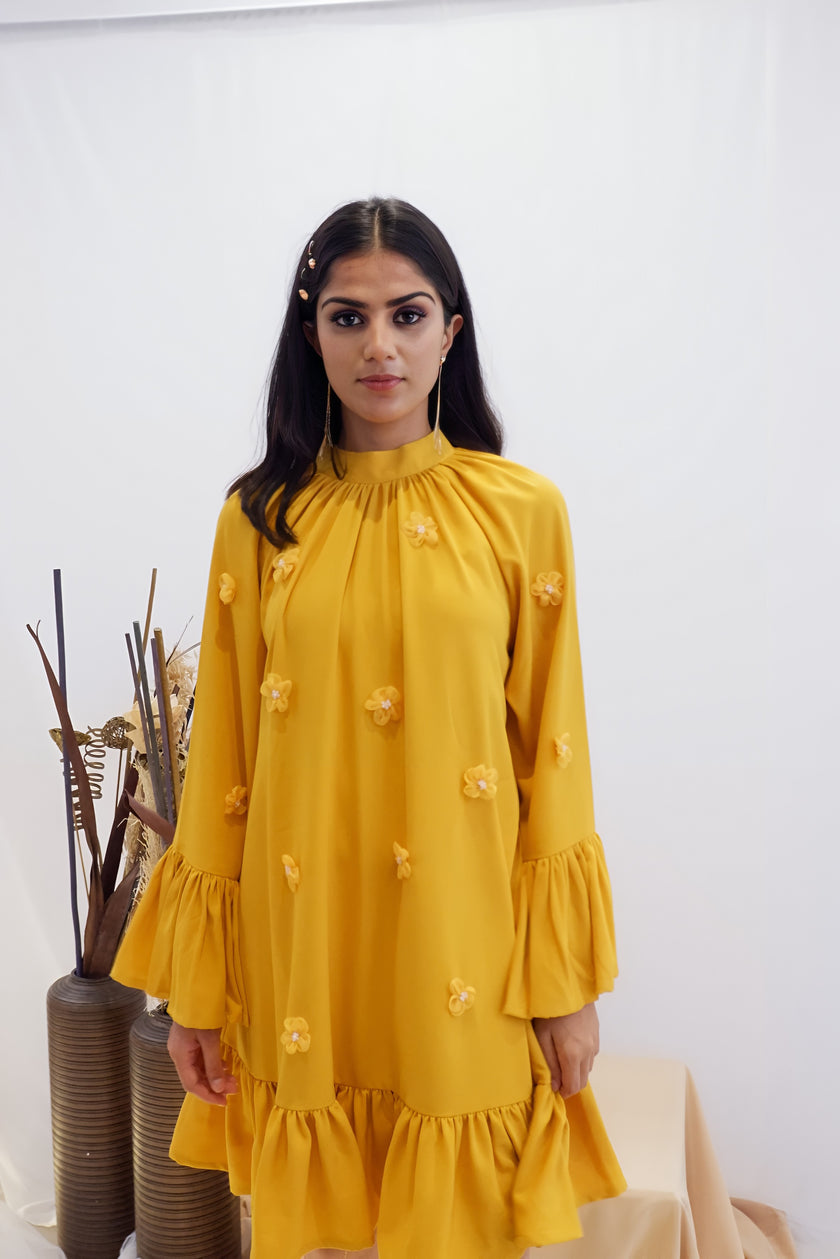 Woman wearing a yellow dress with floral details against a white background. Freo
