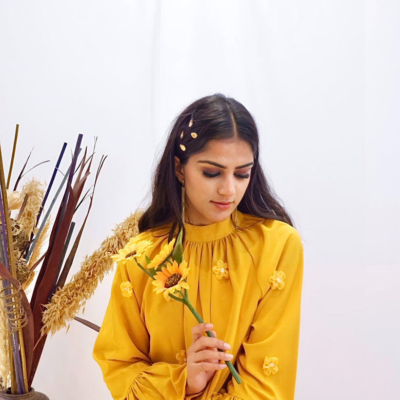 Woman wearing a yellow dress with floral details against a white background. Freo