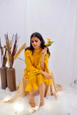 Woman wearing a yellow dress with floral details against a white background. Freo